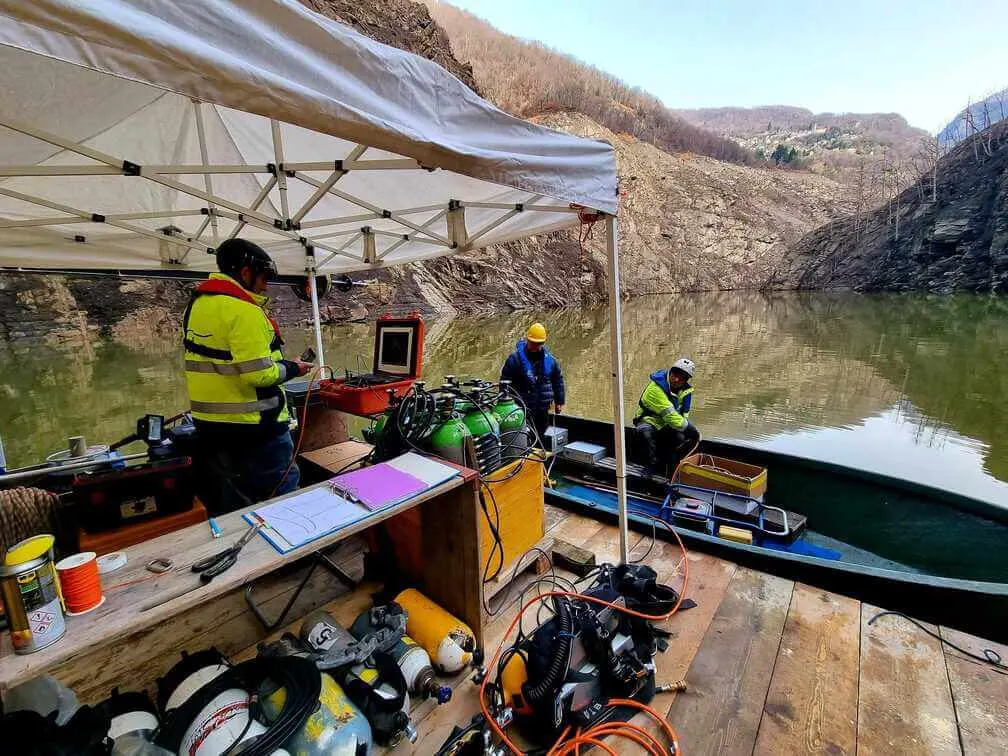 Stazione d'immersione su una zattera con tecnici in alta visibilità, nel bacino della diga