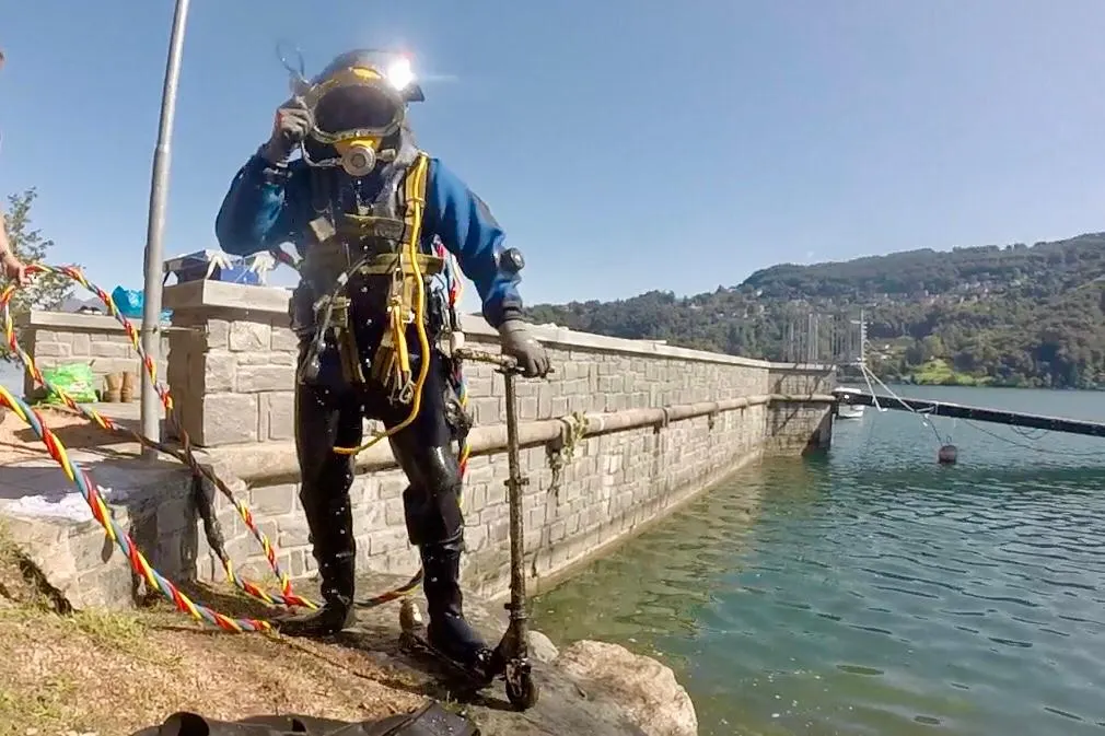 Palombaro con casco e muta stagna sul molo, pronto all'immersione